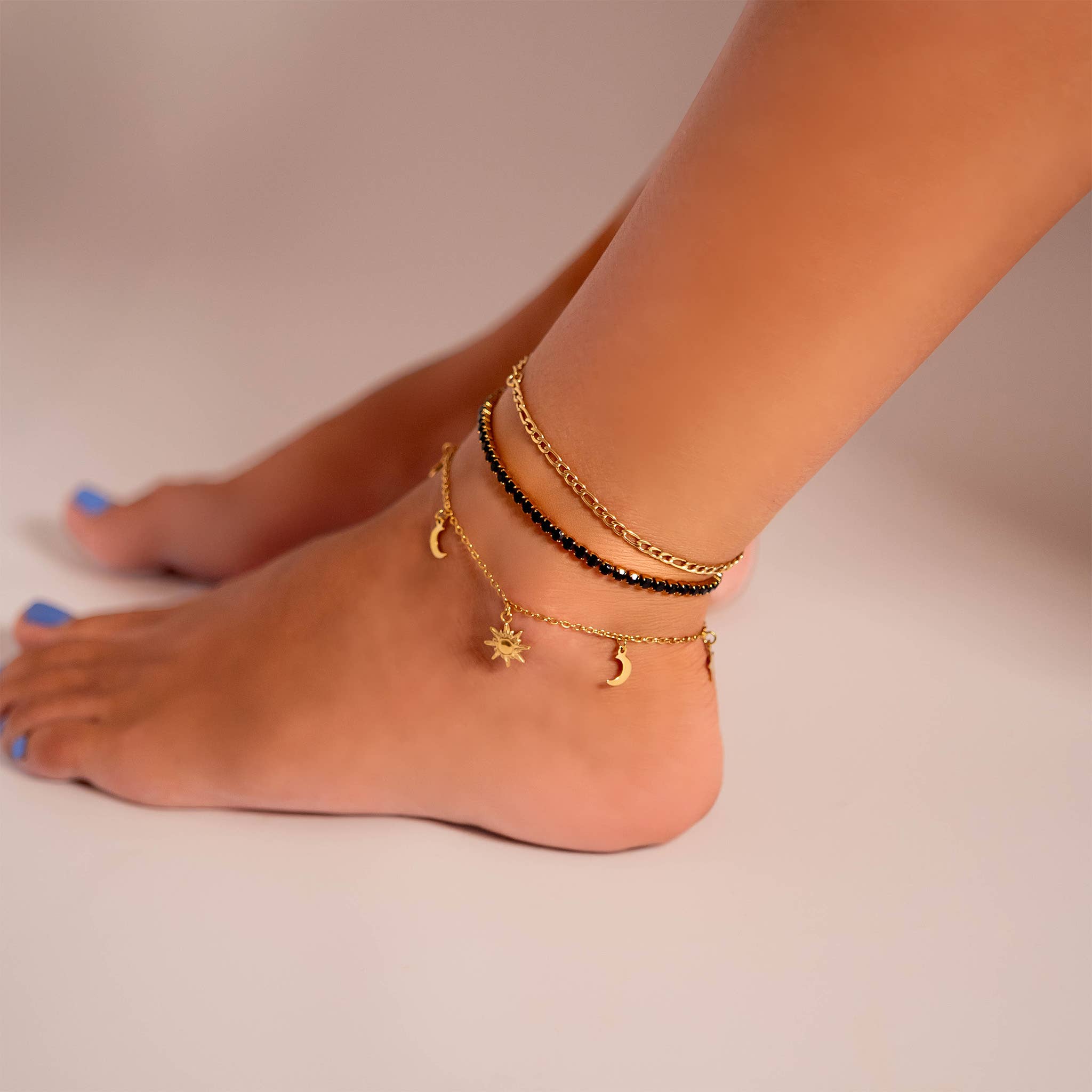 Ankle with multiple gold anklets on a neutral background