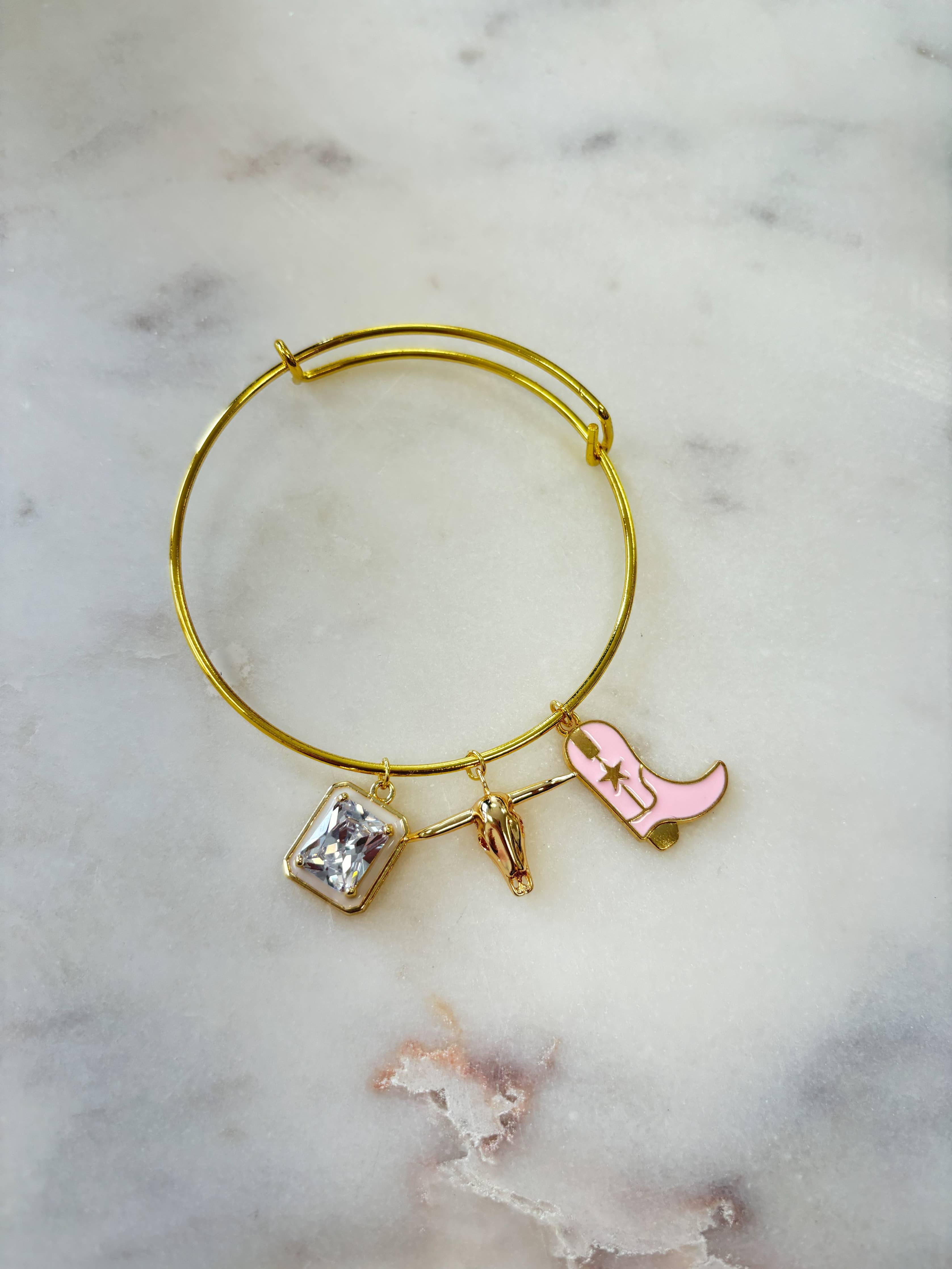 Gold bracelet with charms on a marble surface