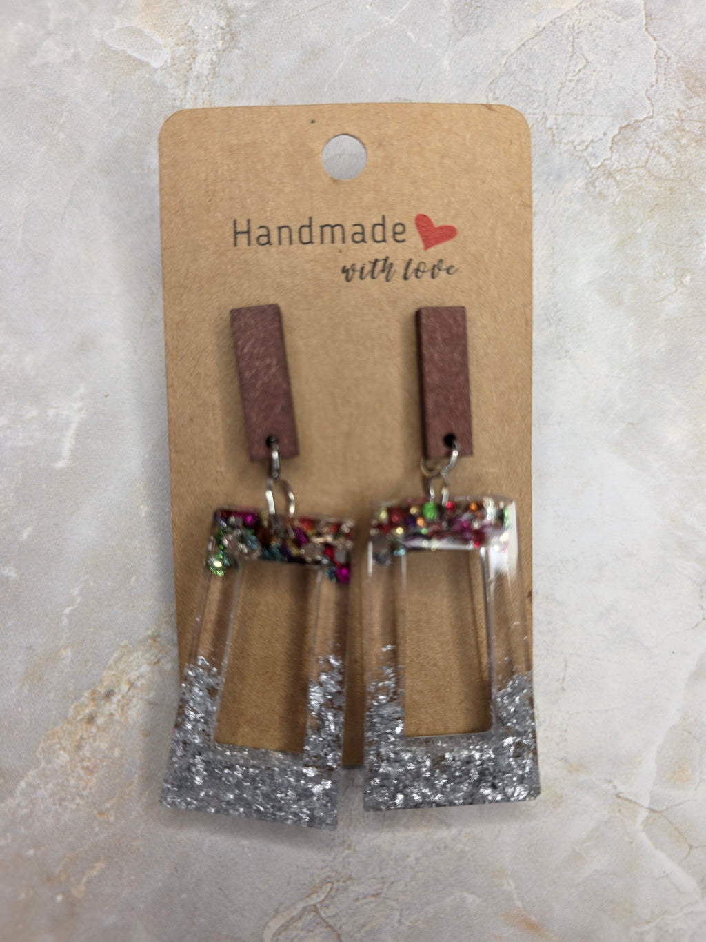 Pair of earrings on a 'Handmade with Love' card against a light marble background
