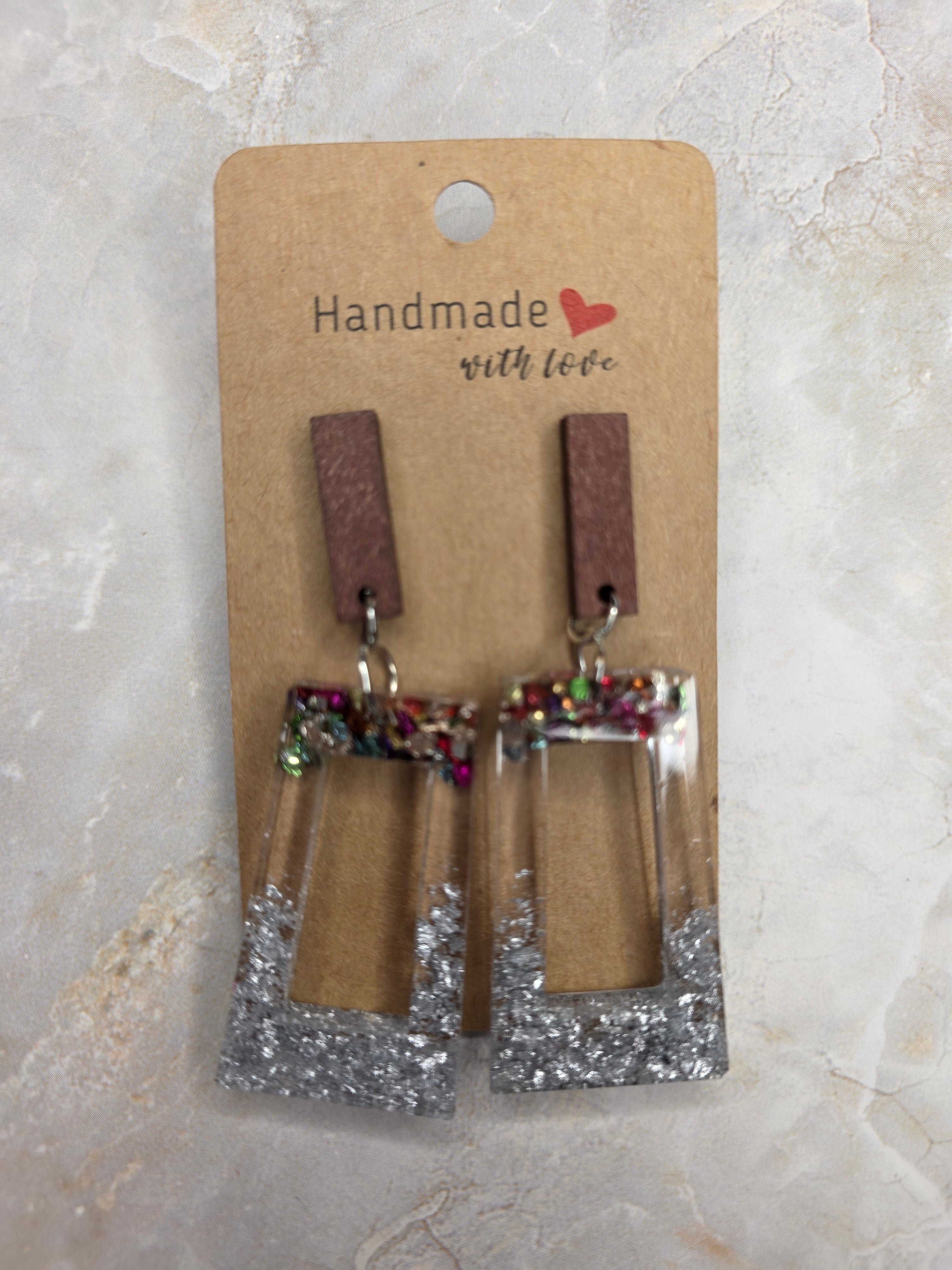 Pair of earrings on a 'Handmade with Love' card against a light marble background